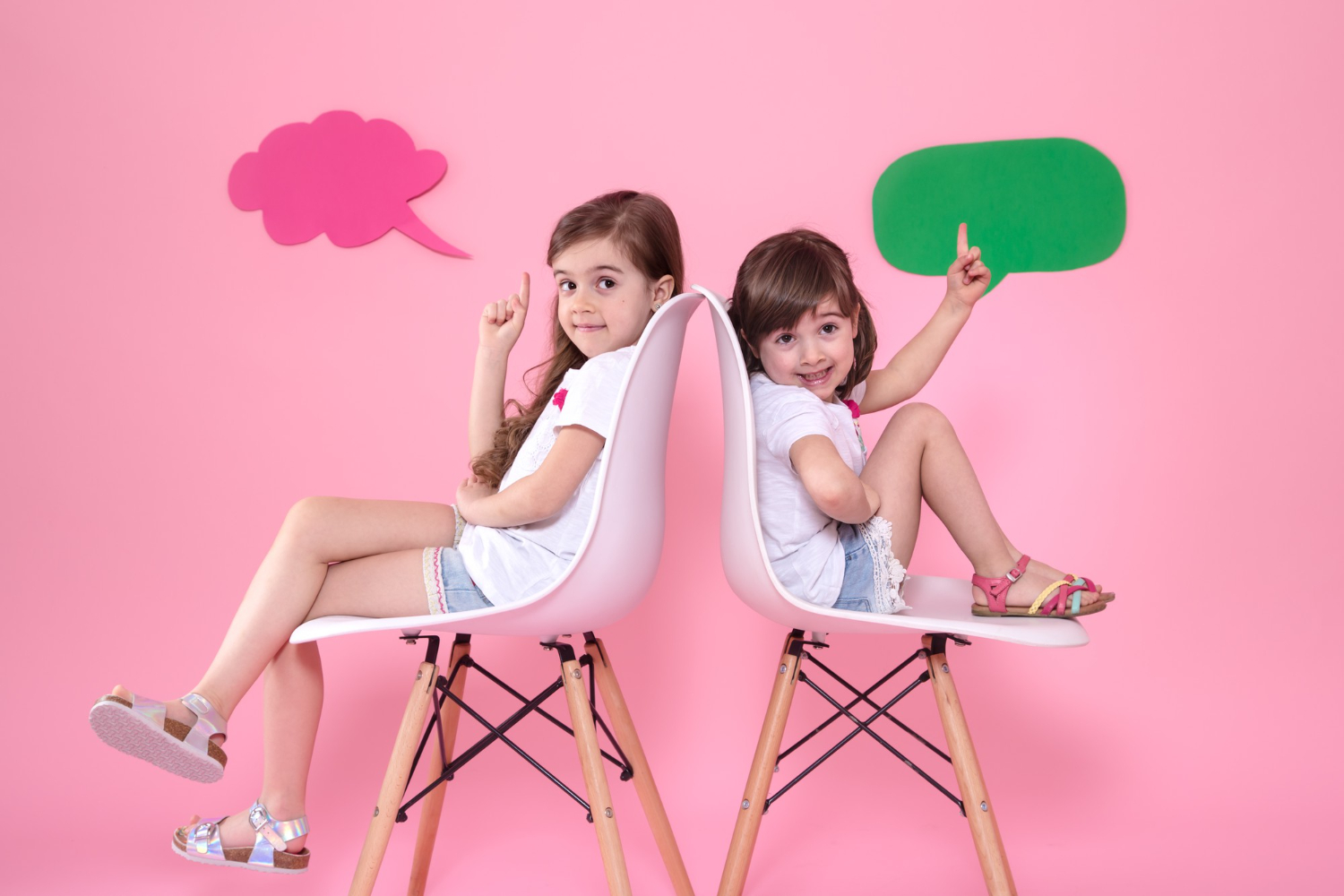 two-little-girls-colored-wall-with-speech-icons